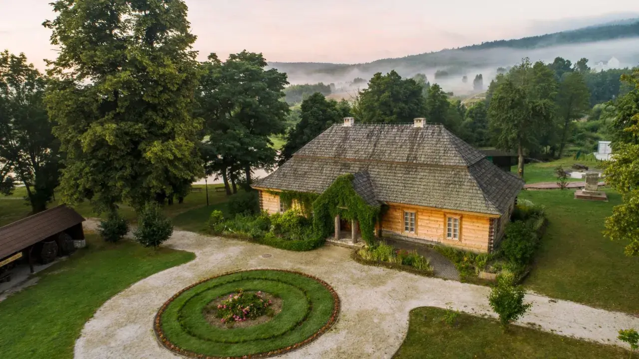 Drewniany dom, otoczony zielenią i mglistym krajobrazem, przypomina bajkowy dom ze szkła.