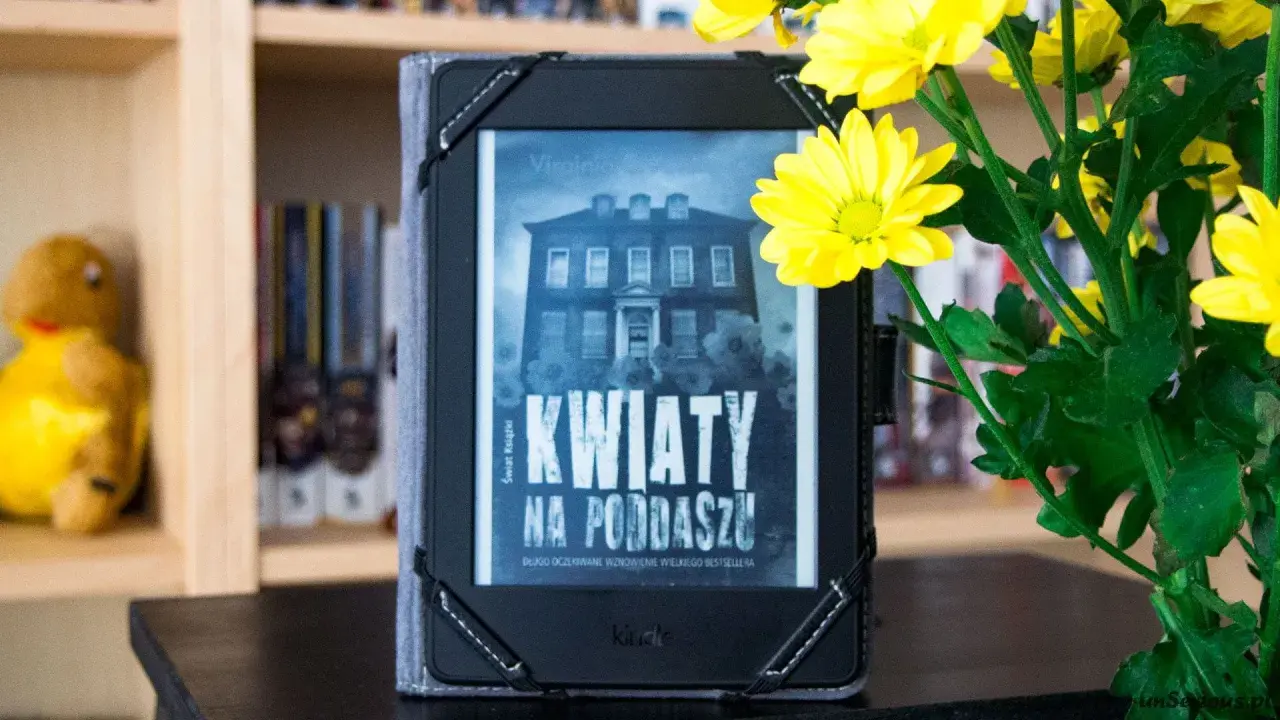 Elektroniczna książka z okładką "Kwiaty na poddaszu" obok bukietu żółtych chryzantem.
