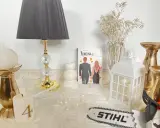 Książka "Rodzina Monet. Diament" wśród świec, złotych ozdób i lampy.
