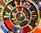 Książki ułożone w spiralę, tworząc piotr kościelny dom wiedzy. Widać tytuły o naukach ścisłych i przyrodniczych.