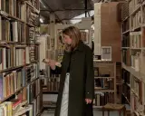Kobieta w antykwariacie przegląda książki psychologiczne, które zmieniają życie. Wśród regałów pełnych literatury szuka inspiracji.