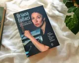 Książka "Kapelusz cały w czereśniach" Oriany Fallaci leży obok okularów i innych książek.