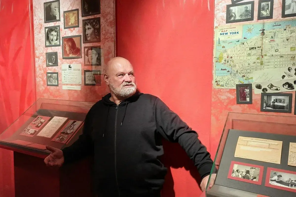 Mężczyzna przy wystawie poświęconej Halinie Poświatowskiej. Widać zdjęcia poetki i fragmenty jej twórczości, w tym wiersze.